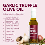 SydSauce Garlic Truffle Olive Oil bottle on a pale pink background with ingredient callouts and food props including garlic, truffle, onion, rosemary, and oil. Large headline reads 'GARLIC TRUFFLE OLIVE OIL'.