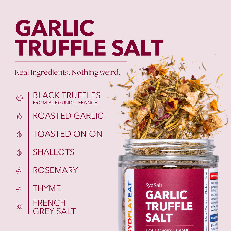 SydSalt Garlic Truffle Salt in a clear glass jar with a dark red label, shown next to a pile of the dried herb mixture on a pale pink background with ingredient callouts.