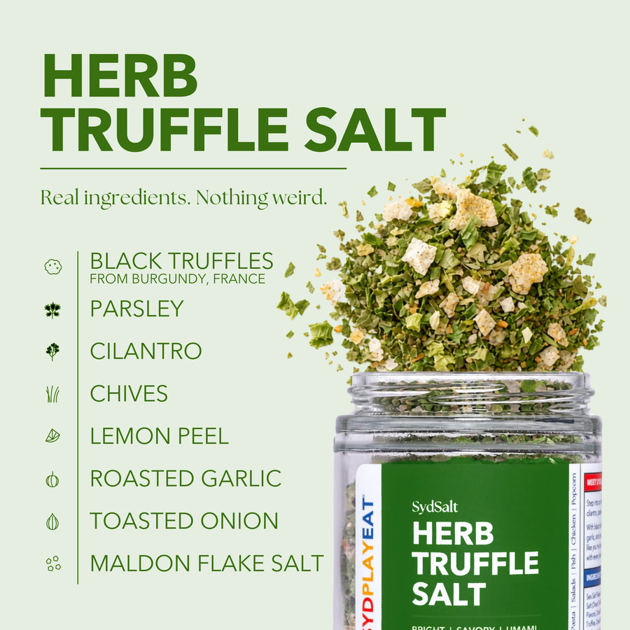 SydSalt Herb Truffle Salt in a clear jar with a green label, shown on a pale green background with ingredient callouts including black truffles from Burgundy, France, parsley, cilantro, chives, lemon peel, roasted garlic, toasted onion, and Maldon flake salt. Herb truffle salt is depicted spilling from the jar.