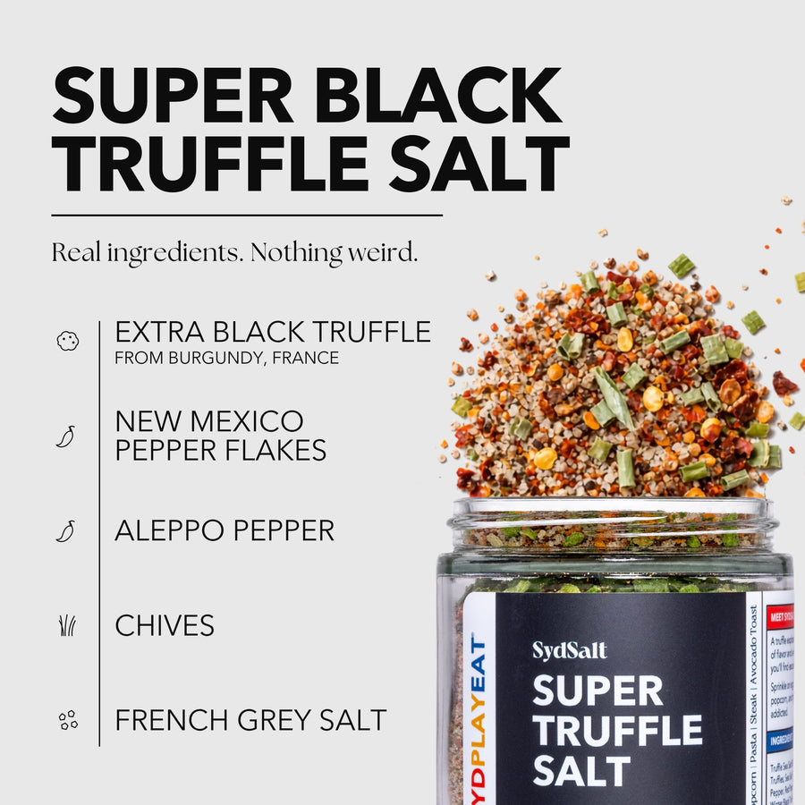 SydSalt Super Black Truffle Salt in a clear glass jar with a black label, shown on a light gray background with ingredient callouts and a pile of the salt spilling out of the jar.