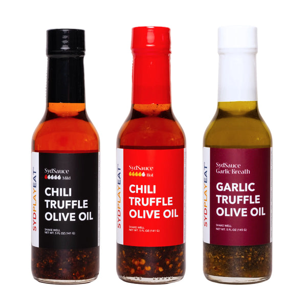 Three glass bottles filled with gourmet chili truffle hot sauce olive oil and garlic olive oil.