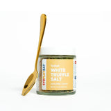 Jar of white truffle salt with a gold spoon on a white background